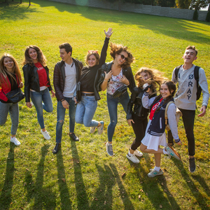 Grupa studentów podskakujących na trawniku