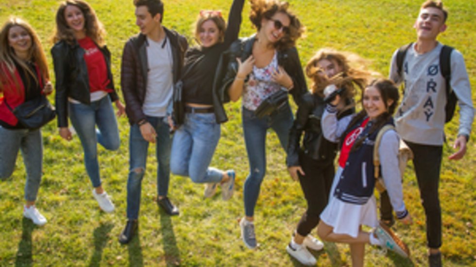 Grupa studentów podskakujących na trawniku